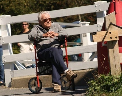 A man in sunglasses rests on the seat of his Drive Nitro rollator walker