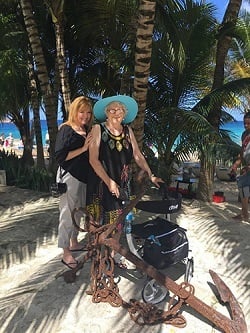 Two women stand in front of palm trees, the older one pushes a Drive Nitro rollator